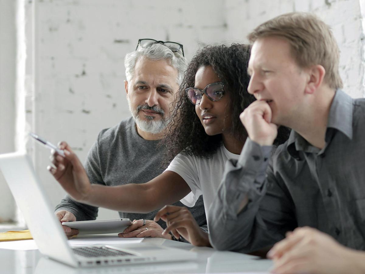 Three people looking at a laptop