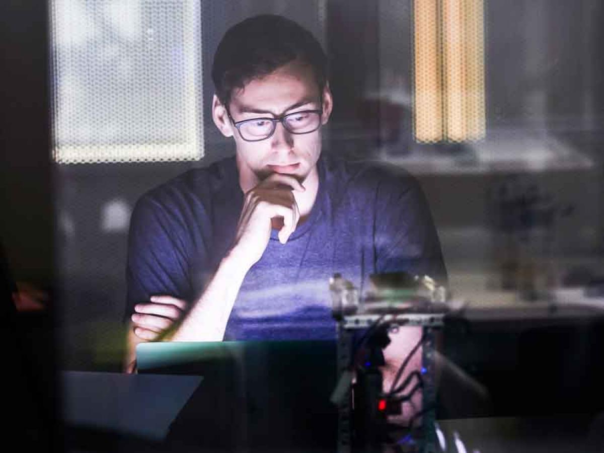 Male in front of a laptop in a dark room. 