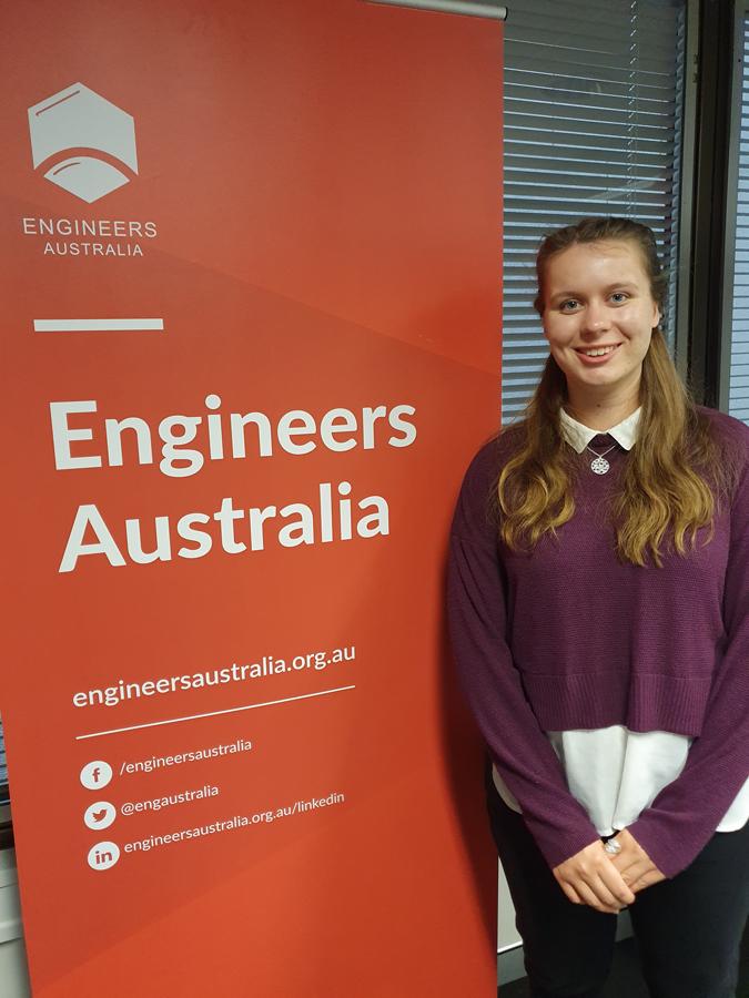 Marceline Overduin standing in front of an orange Engineers Australia pull up banner