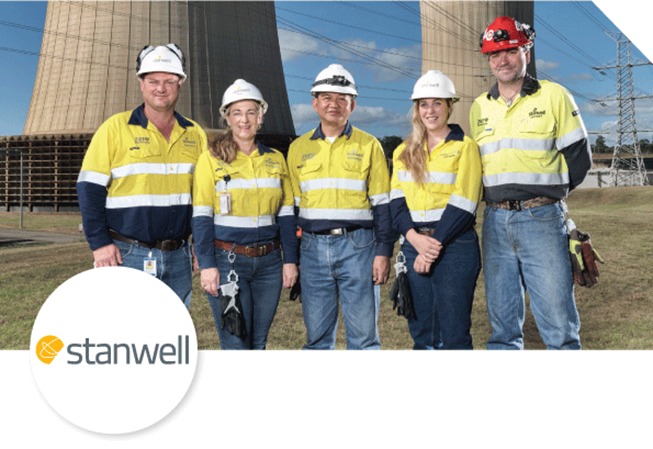5 people wearing high vis yellow and hard hats in front of cooling plant towers