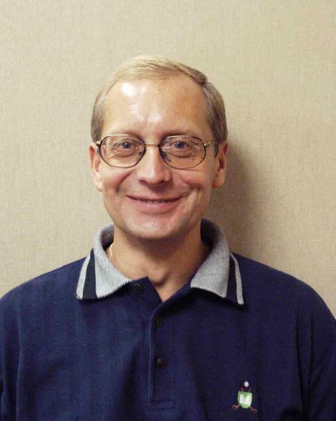 Wojciech Chojnacki smiling at the camera wearing a blue shirt