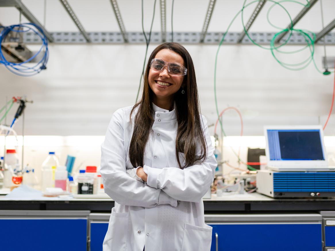 Young female student smiling with her arms crossed in a lab