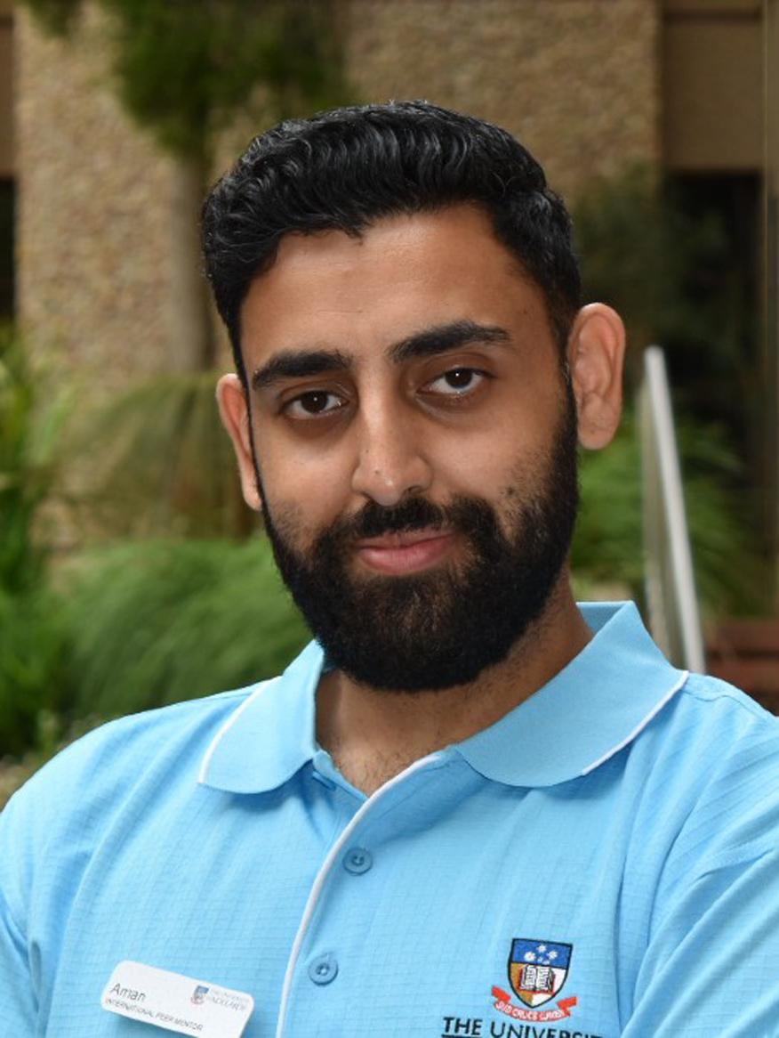 Photo of Aman Dhir, a man with black hair and a beard wearing a light blue tshirt with University of Adelaide logo