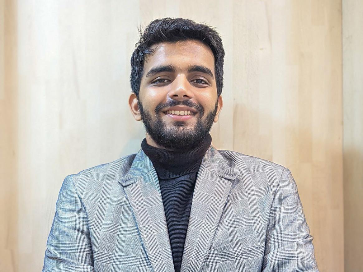 image of a man with black hair wearing a suit jacket and a high necked jumper