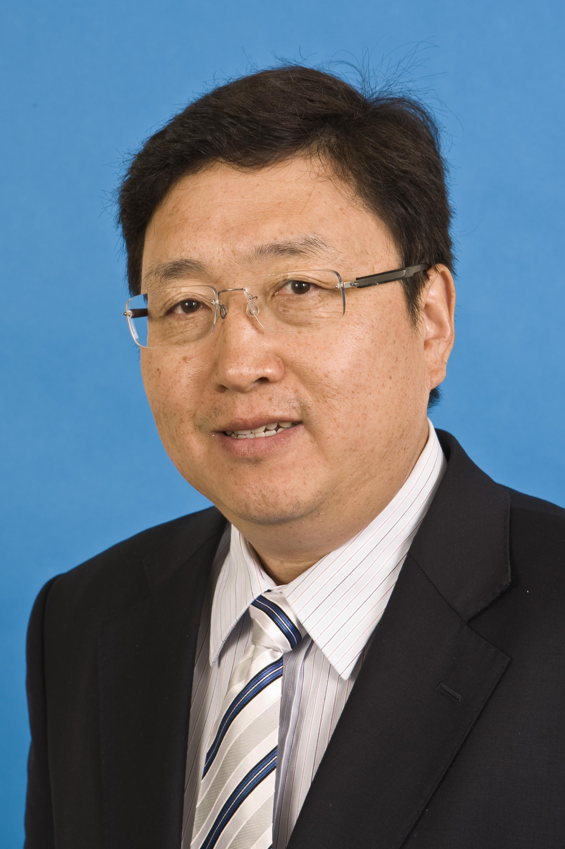 Professor Qiao (male) in black jacket, striped tie, glasses, facing camera