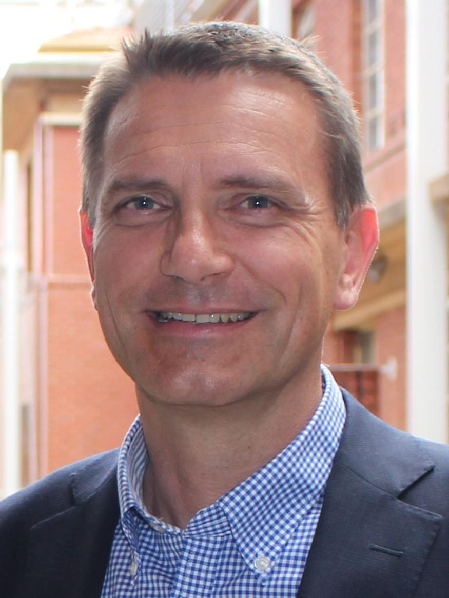 Man in blue and white shirt smiling at camera