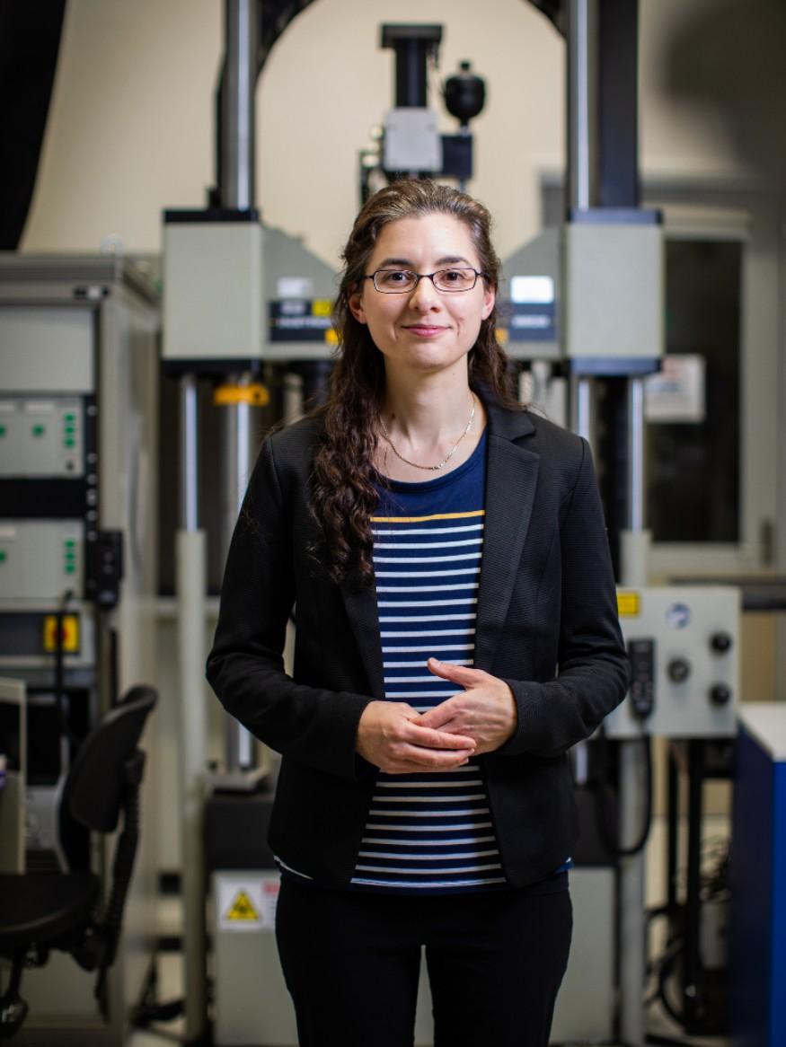 Woman in striped top, black jacket, glasses, facing camera