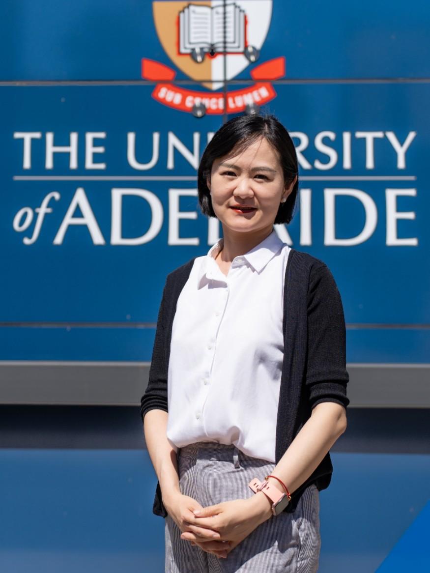Woman in white shirt and dark cardigan facing the camera