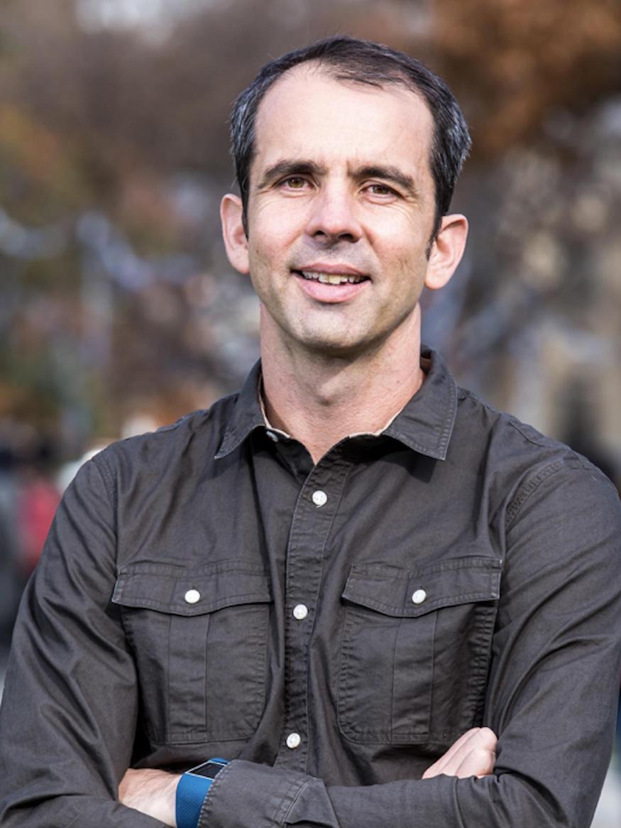 photo of a man outside wearing a dark coloured shirt with buttons and pockets
