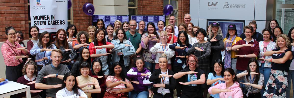 IWD 2021 - large group of ECMS women posing together with their arms in an "equals" shap