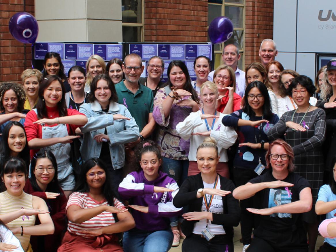 IWD 2021 - large group of ECMS women posing together with their arms in an "equals" shap
