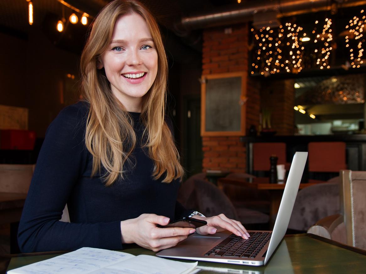 Young business woman sitting with a laptop, phone and notebook